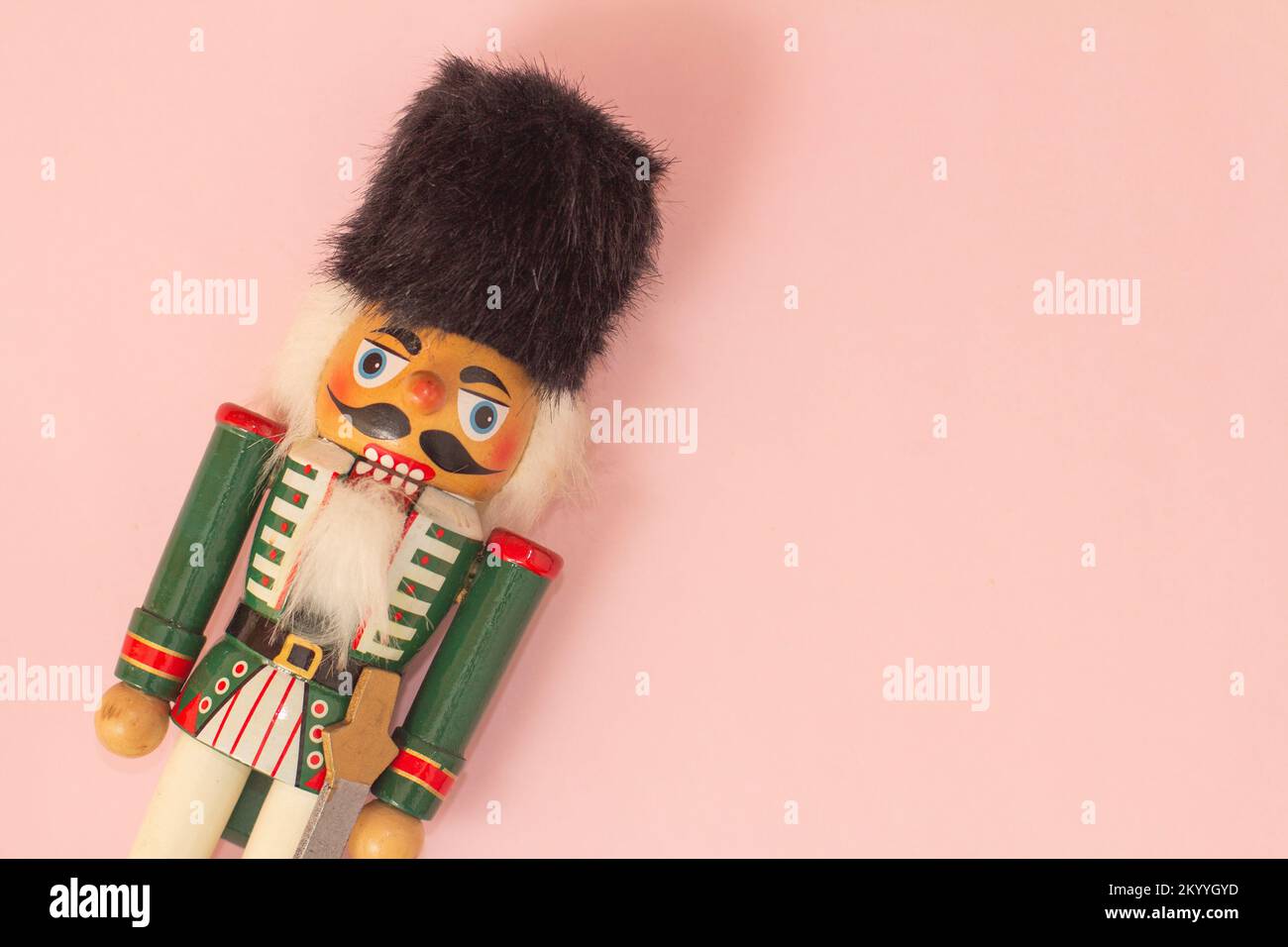 Interesting beautiful christmas nutcracker soldier on pink colored paper surface texture with copy space Stock Photo