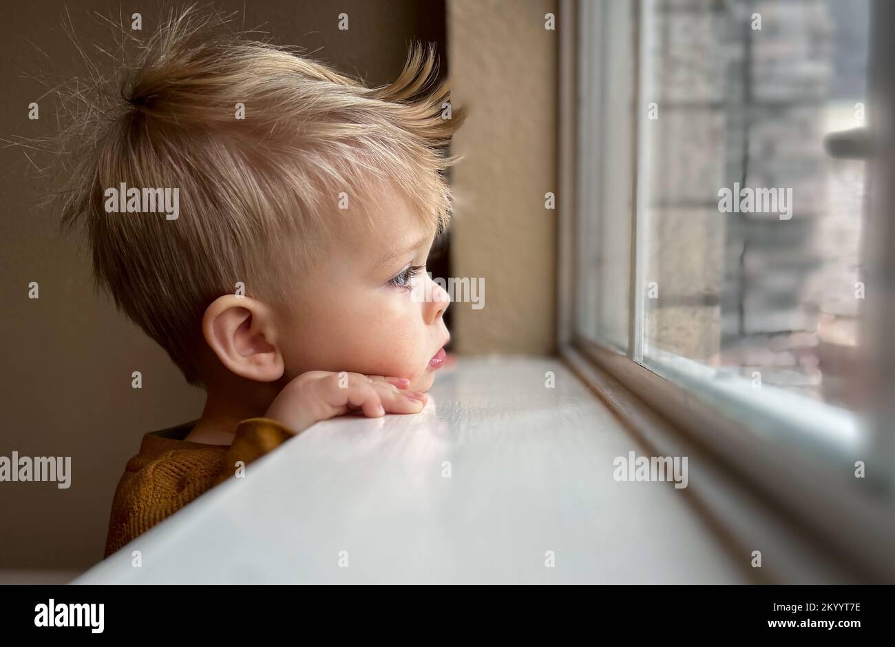 Cute little toddler looking at the window at home, close up portrait  Stock Photo