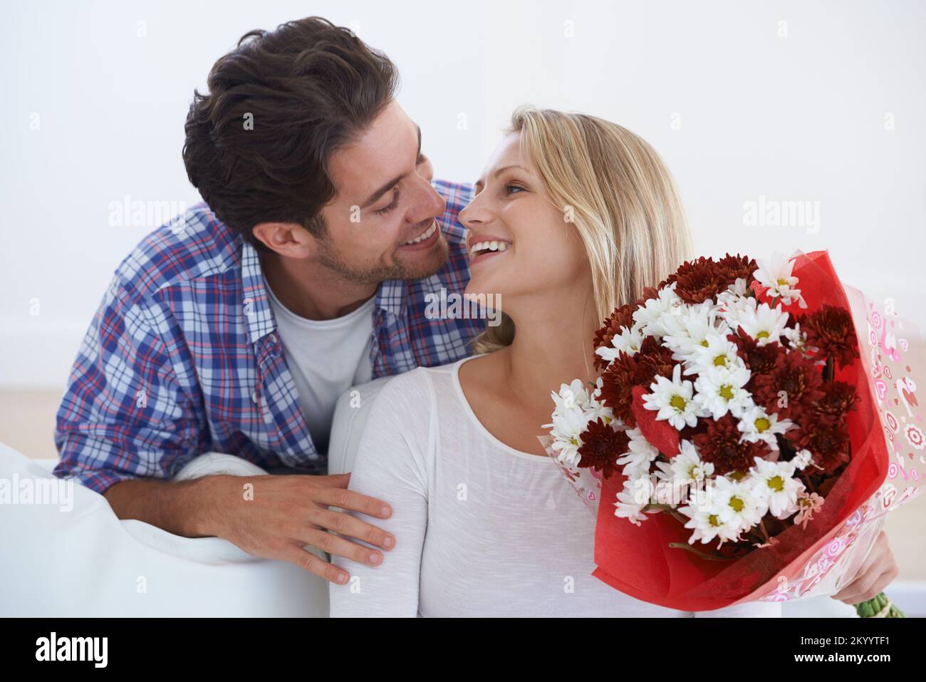For my love. a man suprsing his partner with flowers at home. Stock Photo