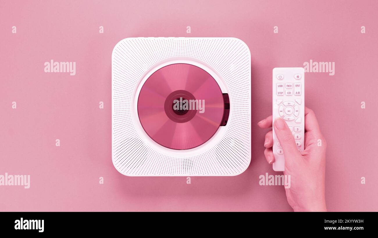 Color of year 2023 Viva Magenta. Image with hand holding controller for stylish portable compact CD player with disc is toned in pantone color. New Fa Stock Photo