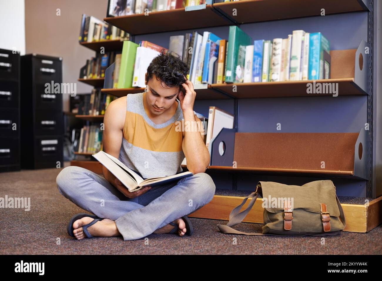 Hes studying really hard for the finals. young college student sitting on the floor of