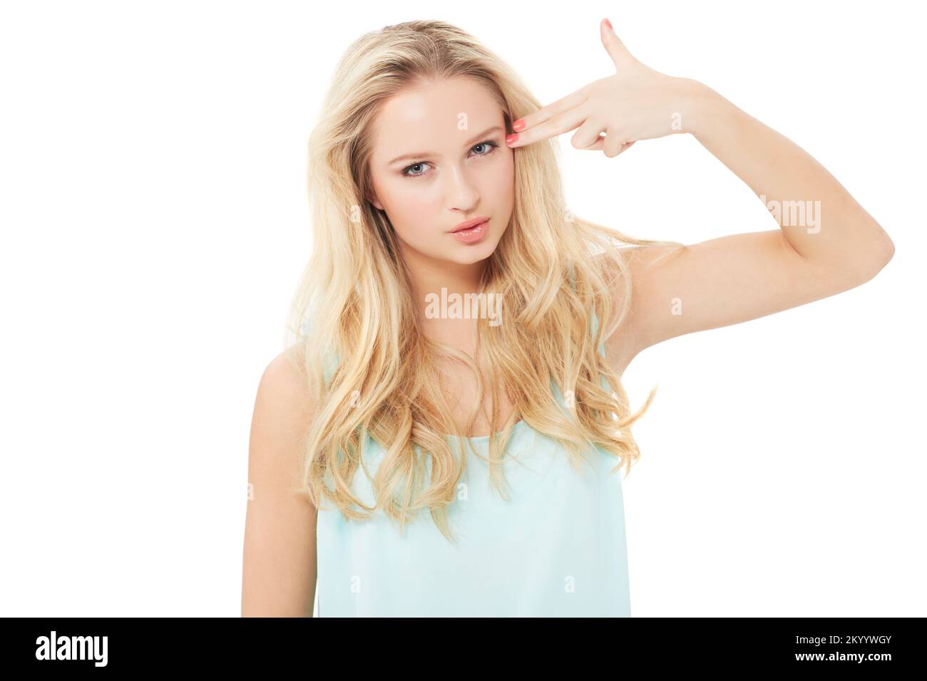 Kill me now, please. A pretty young woman making a gun gesture and aiming her fingers at her head - isolated. Stock Photo