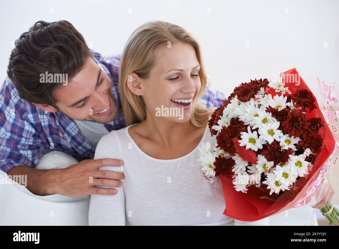 Its just you and me. a man suprsing his partner with flowers at home. Stock Photo