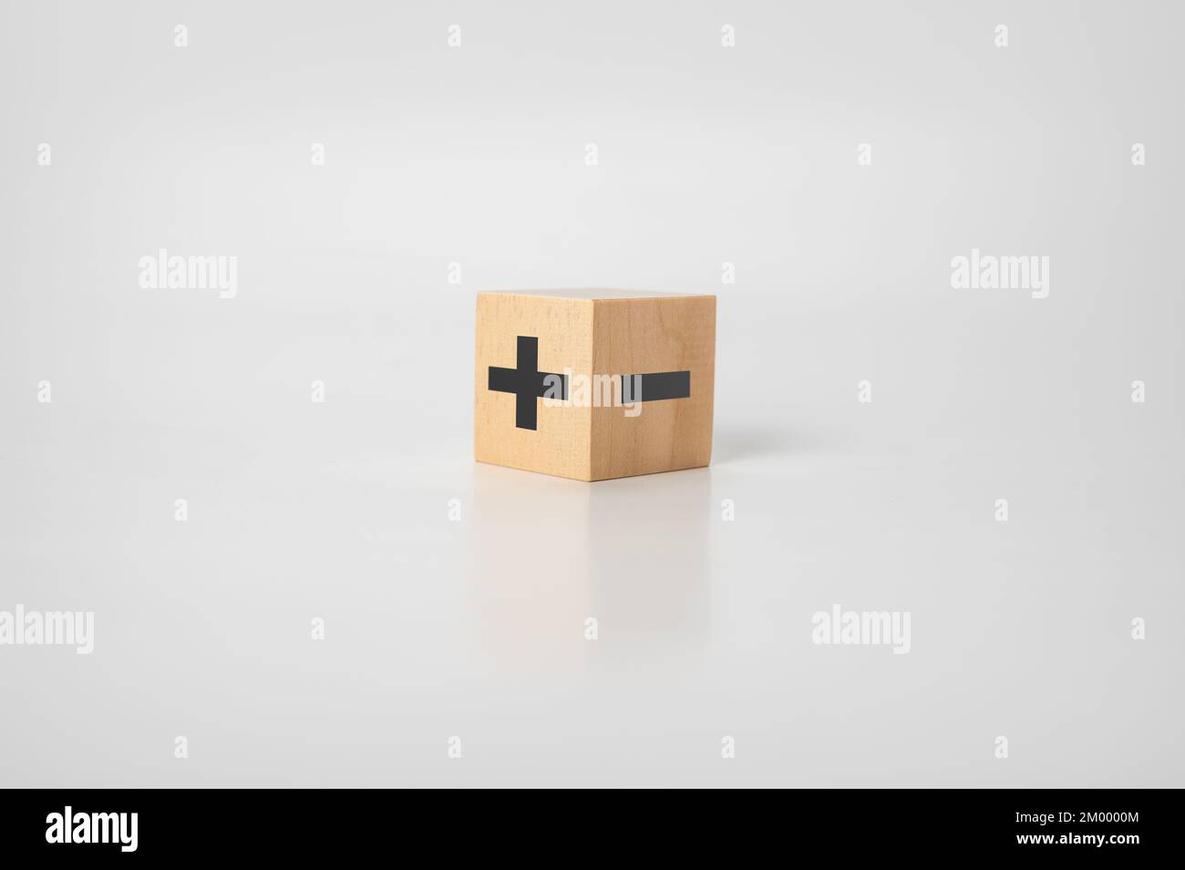 wood cube with plus and minus on gray background. opposites concept. analysis of good and bad. pro and con. Stock Photo