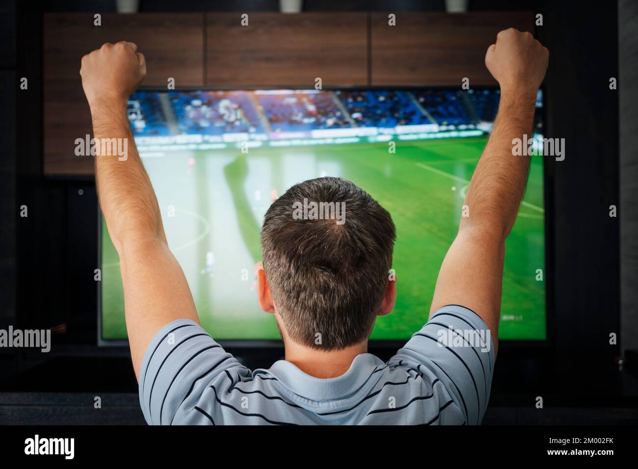Goal. Man watching football match on television at home. emotional fan watching football at night, view from the back Stock Photo