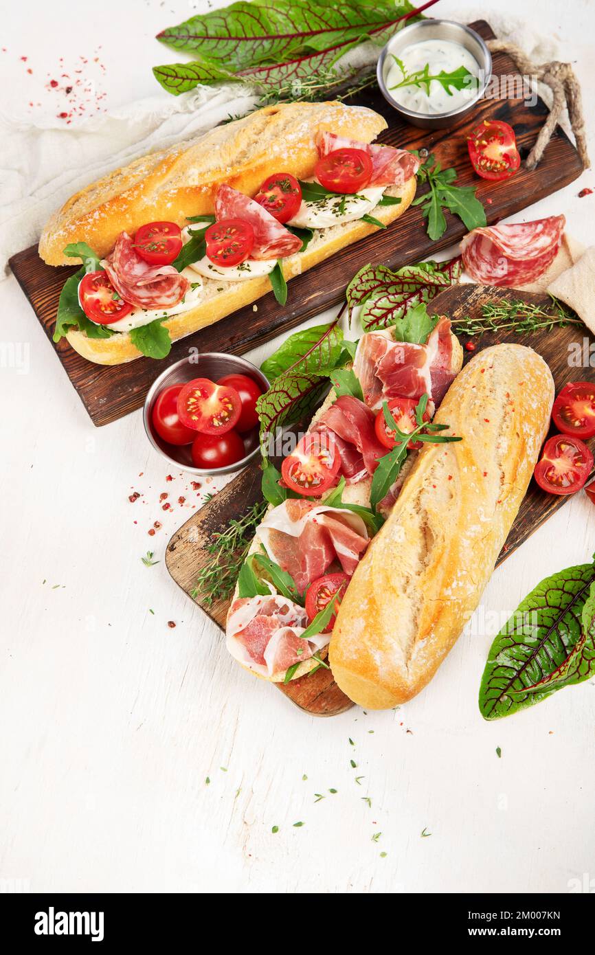 Two baguette sandwiches with salami, mozzarella cheese, lettuce