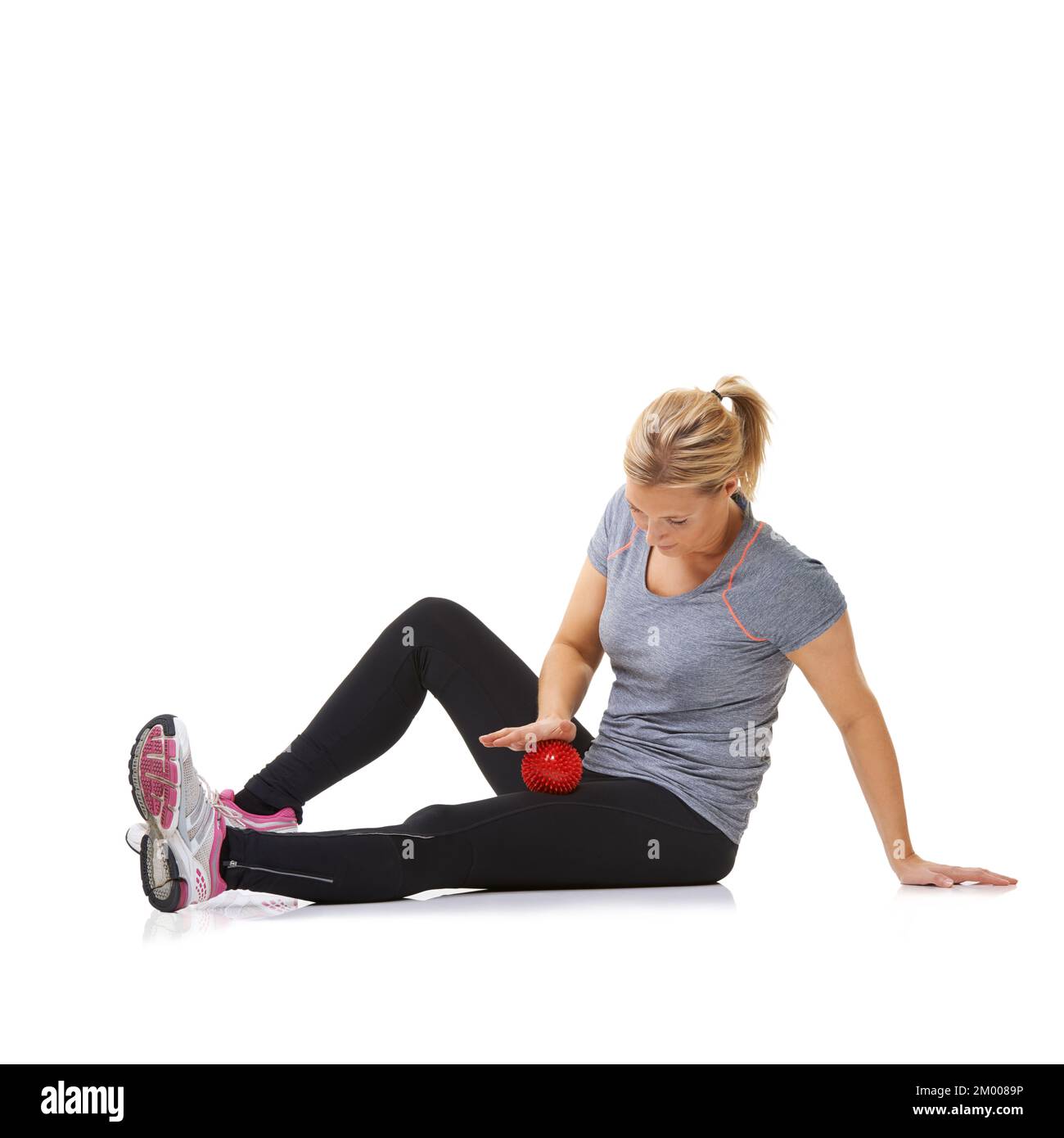 Rolling out her inner thighs. A young woman using an exercise ball to