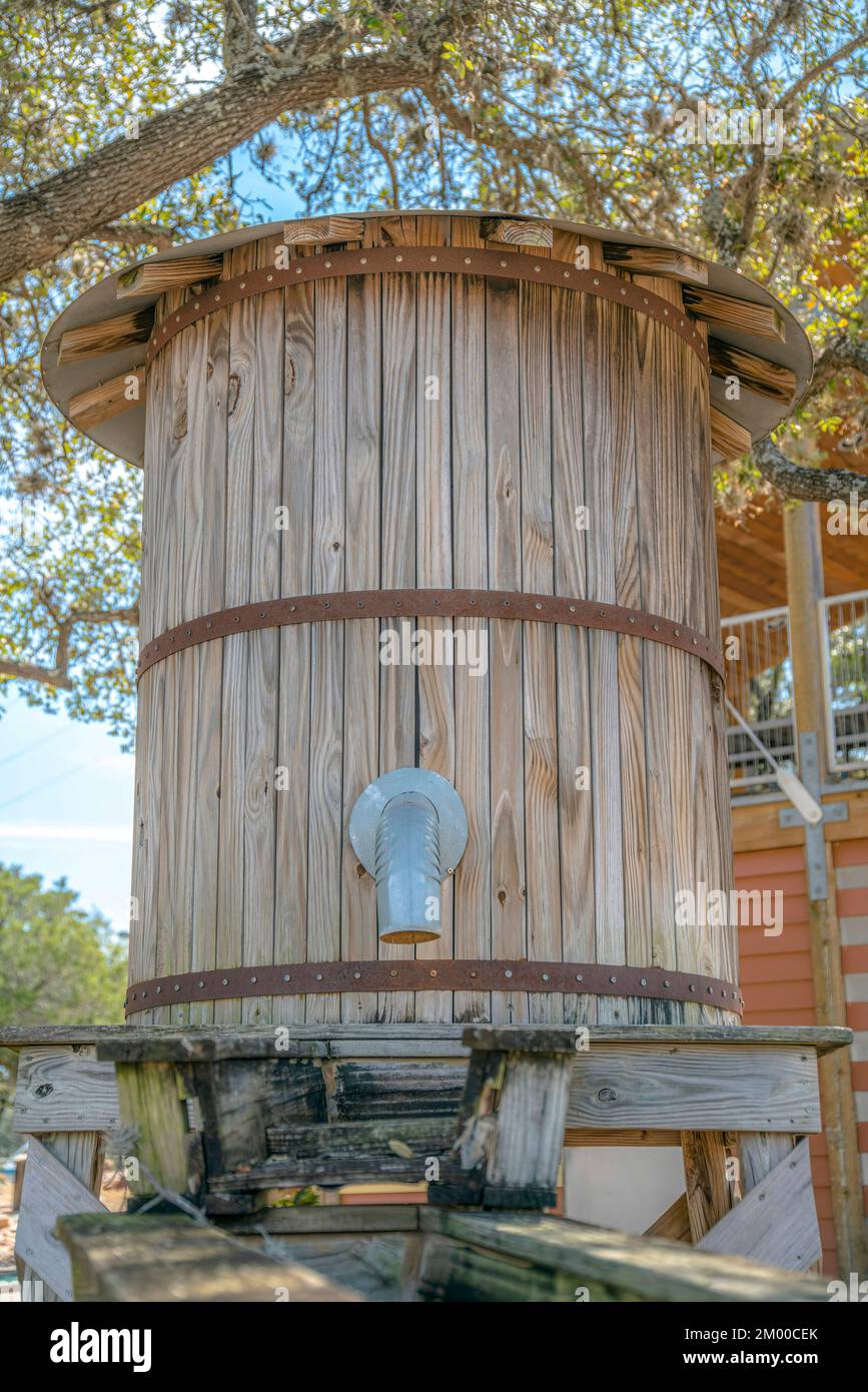 Close-up of a wooden water tank with pipes and water ways at the front- Lake Austin, Austin, Texas. Timber water tank against the trees and house at t Stock Photo