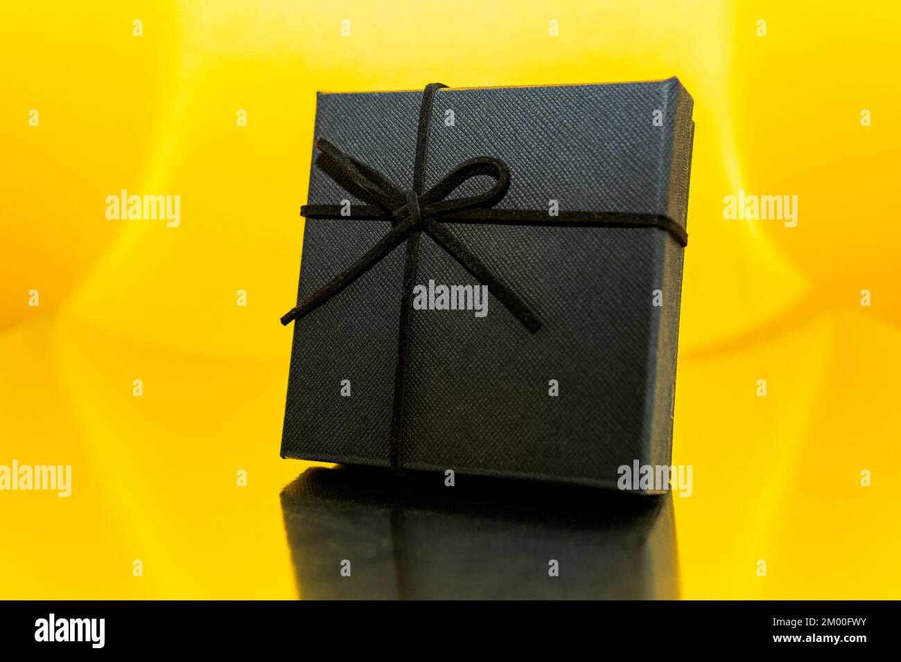 Dark present box over a shiny yellow background Stock Photo - Alamy