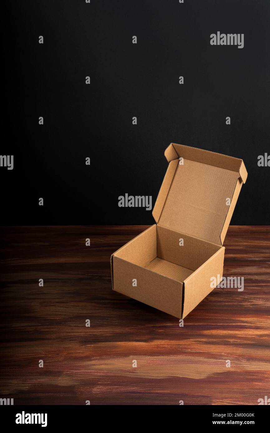 Cardboard box on a dark rustic wooden background in vertical view with copy space Stock Photo