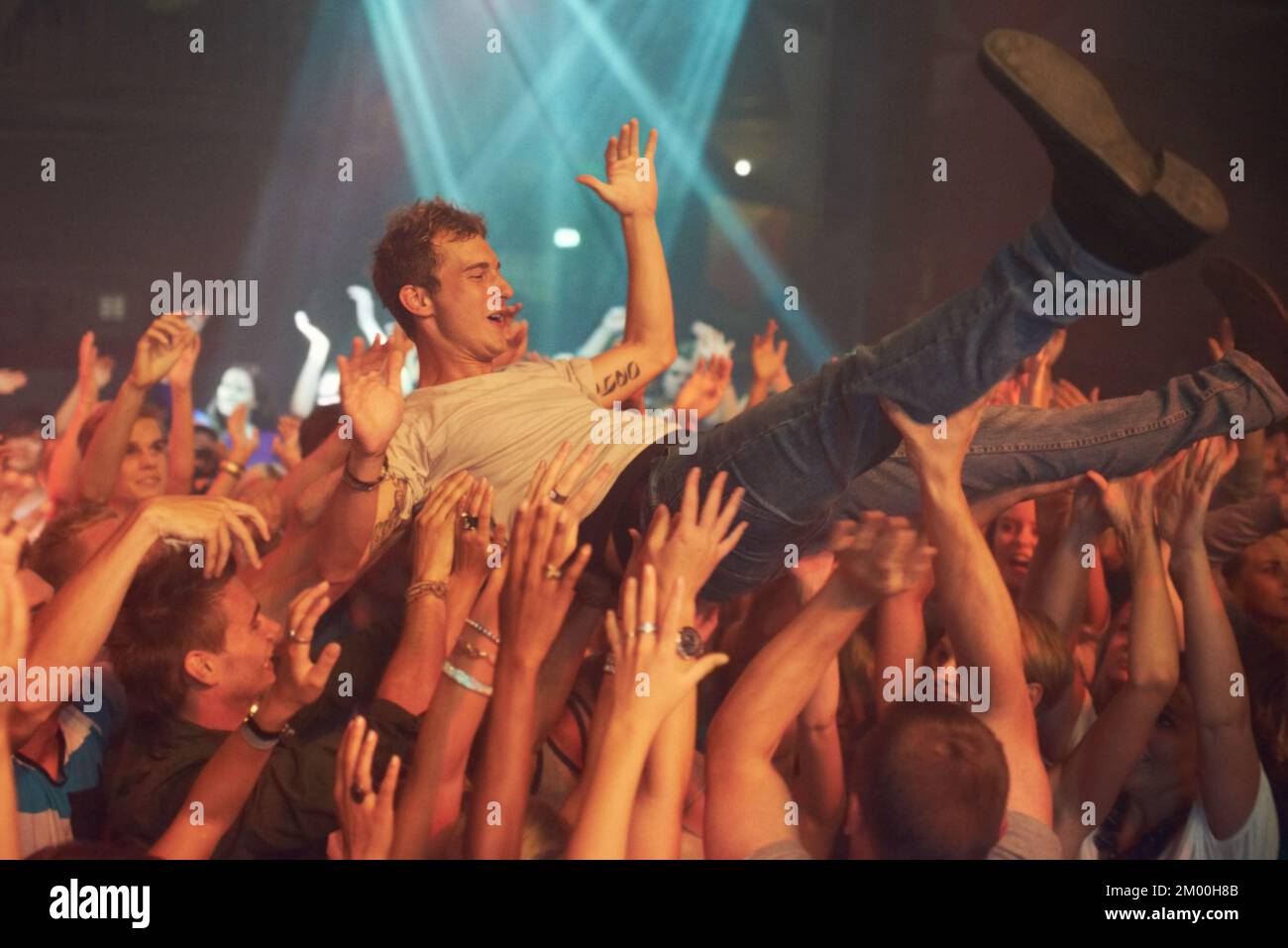 Music, party and crowd surfing with man at concert for rock, celebration and festival. Energy, light and dance with audience listening to live band Stock Photo