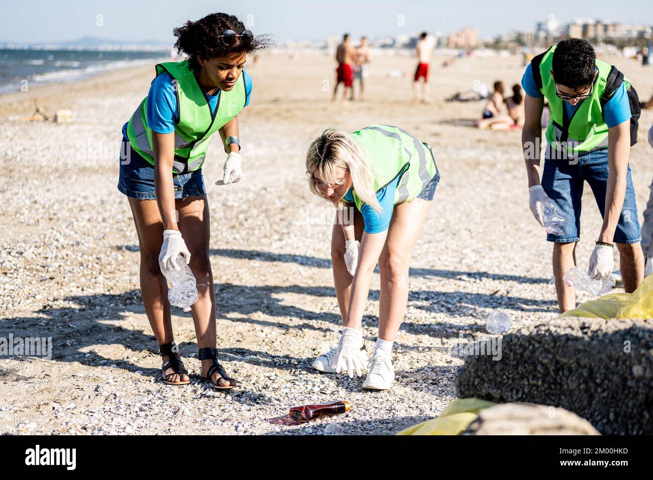 Diverse people cleaning up the beach, volunteers collecting the waste ...