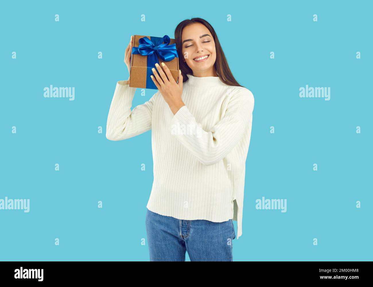 Happy smiling young woman in warm sweater holding gift box with Christmas present Stock Photo