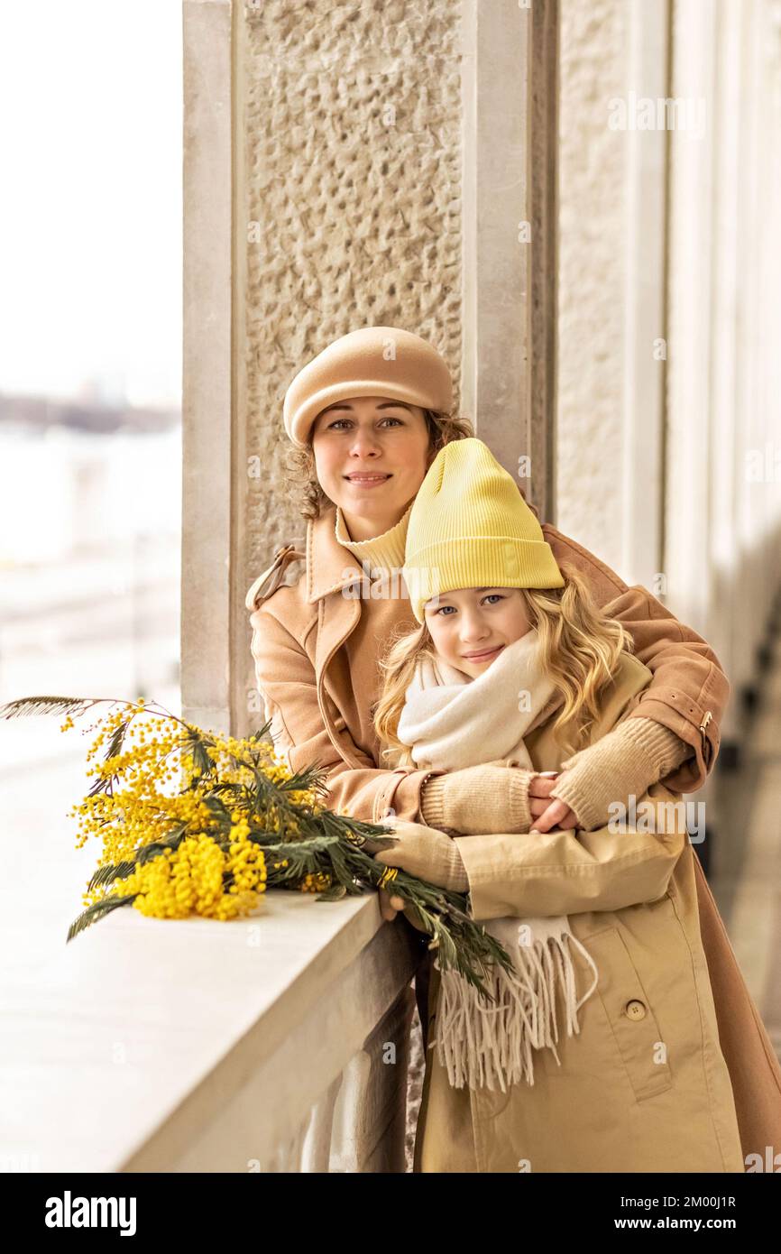 Portrait of mother and little daughter with mimosa bouquet in spring park. Spring, International Women's Day March 8. Stock Photo
