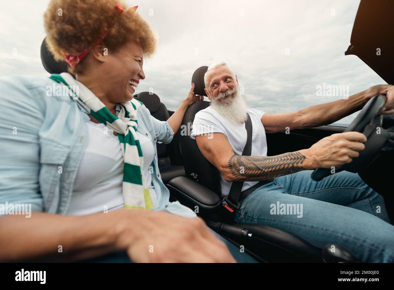 Happy elderly couple having fun driving convertible car during a road trip - Travel people lifestyle concept Stock Photo