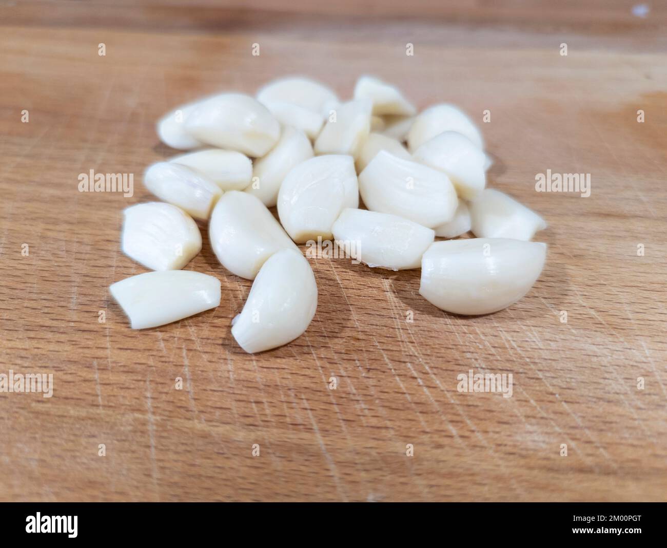 fresh peeled garlic on a cutting board in a kitchen Stock Photo