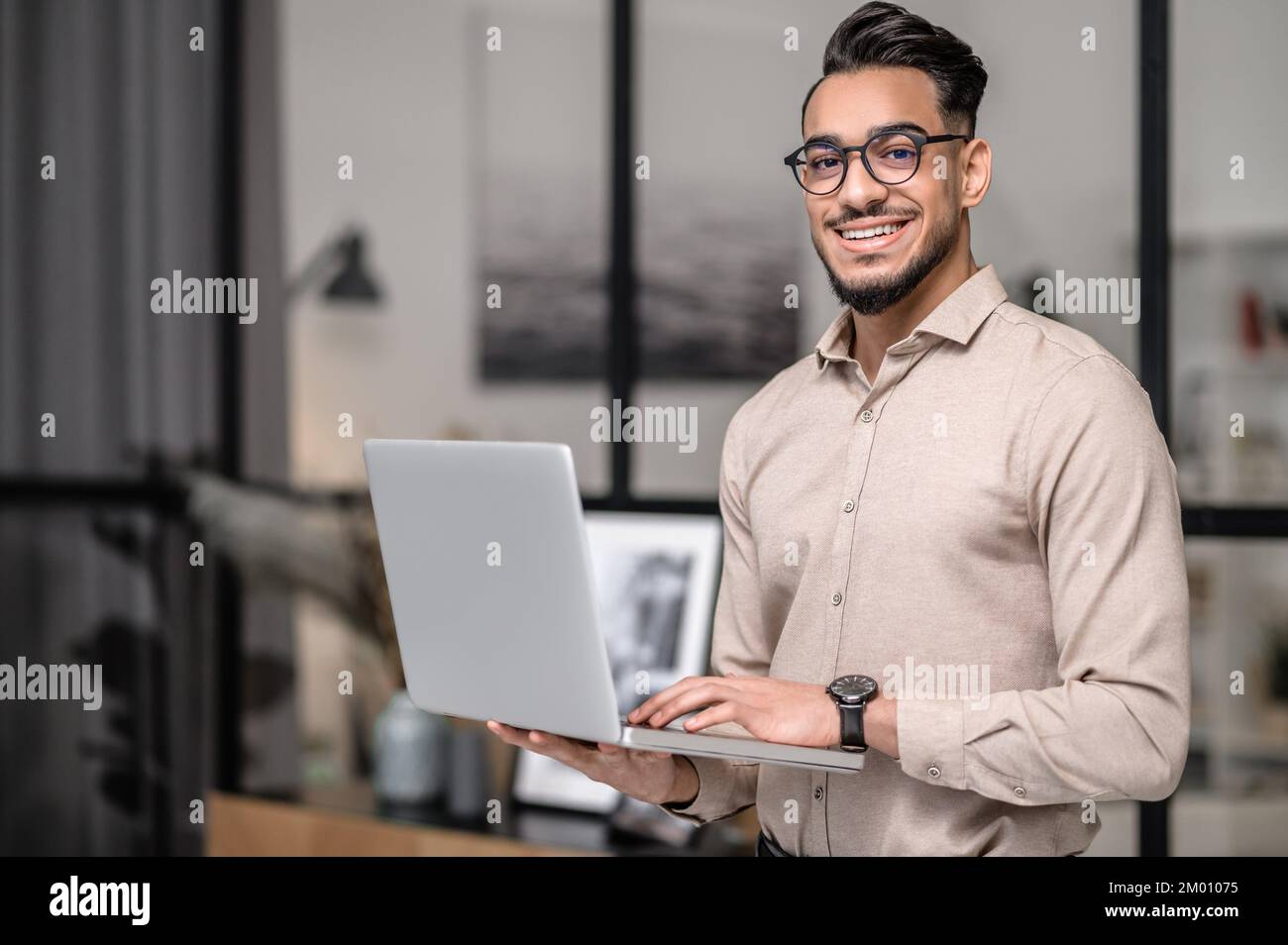 Good mood. A young businessman with a laptop looking cotented. Stock Photo