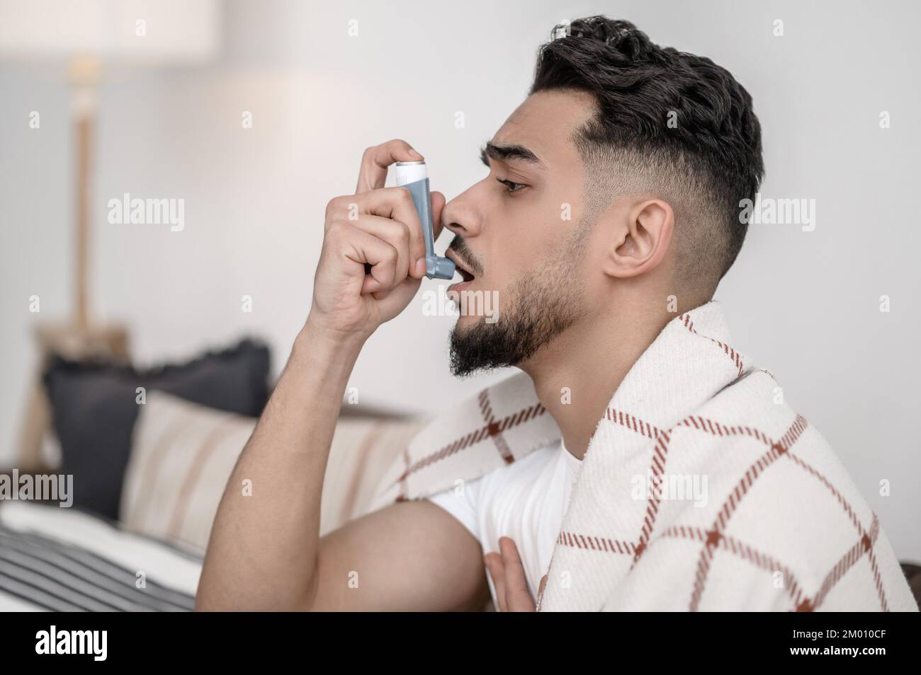 Running nose. A sick man spraying nasal drops to his nose Stock Photo