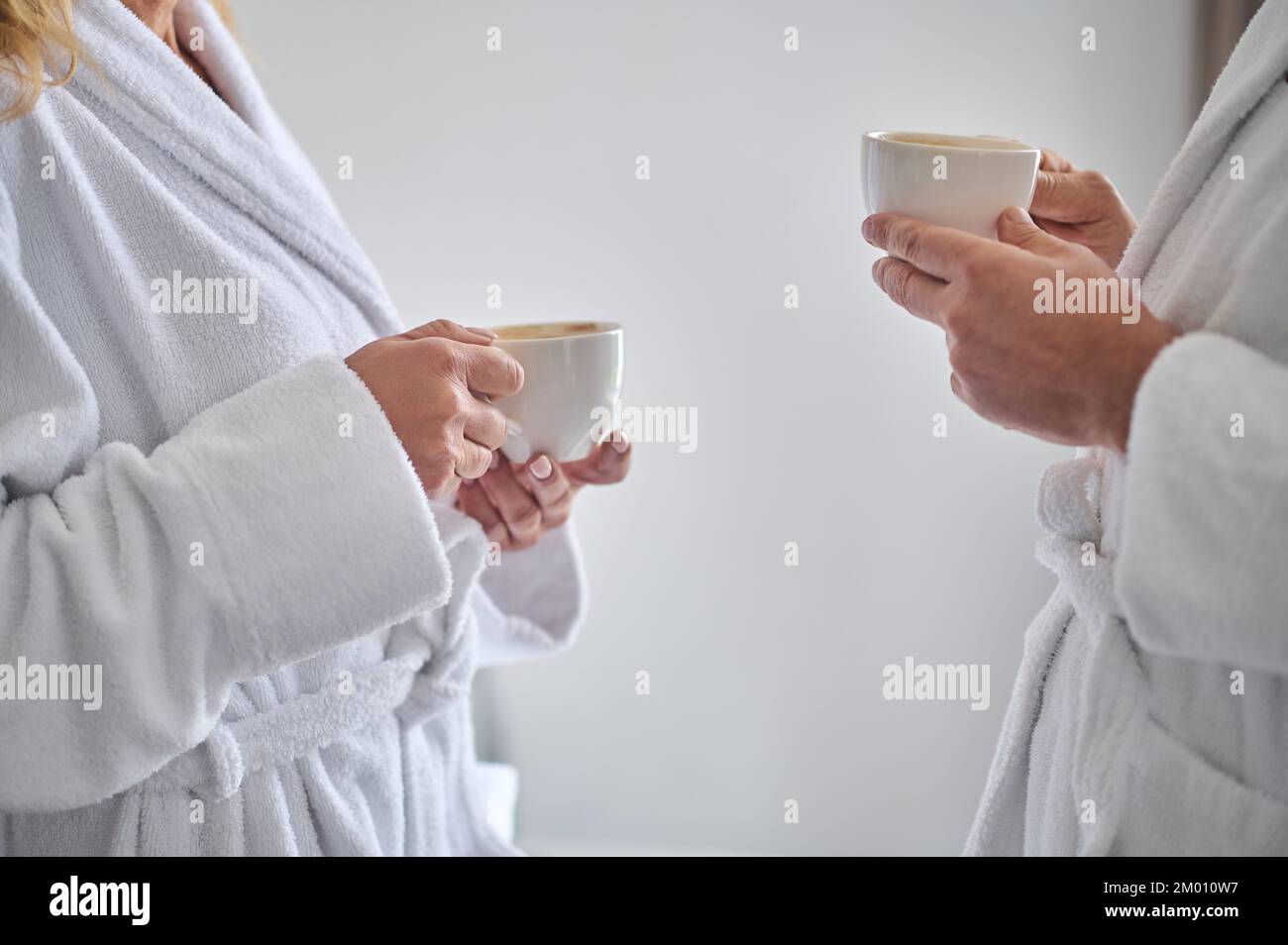Coffee time. Close up picture of two people with coffee mugs standing