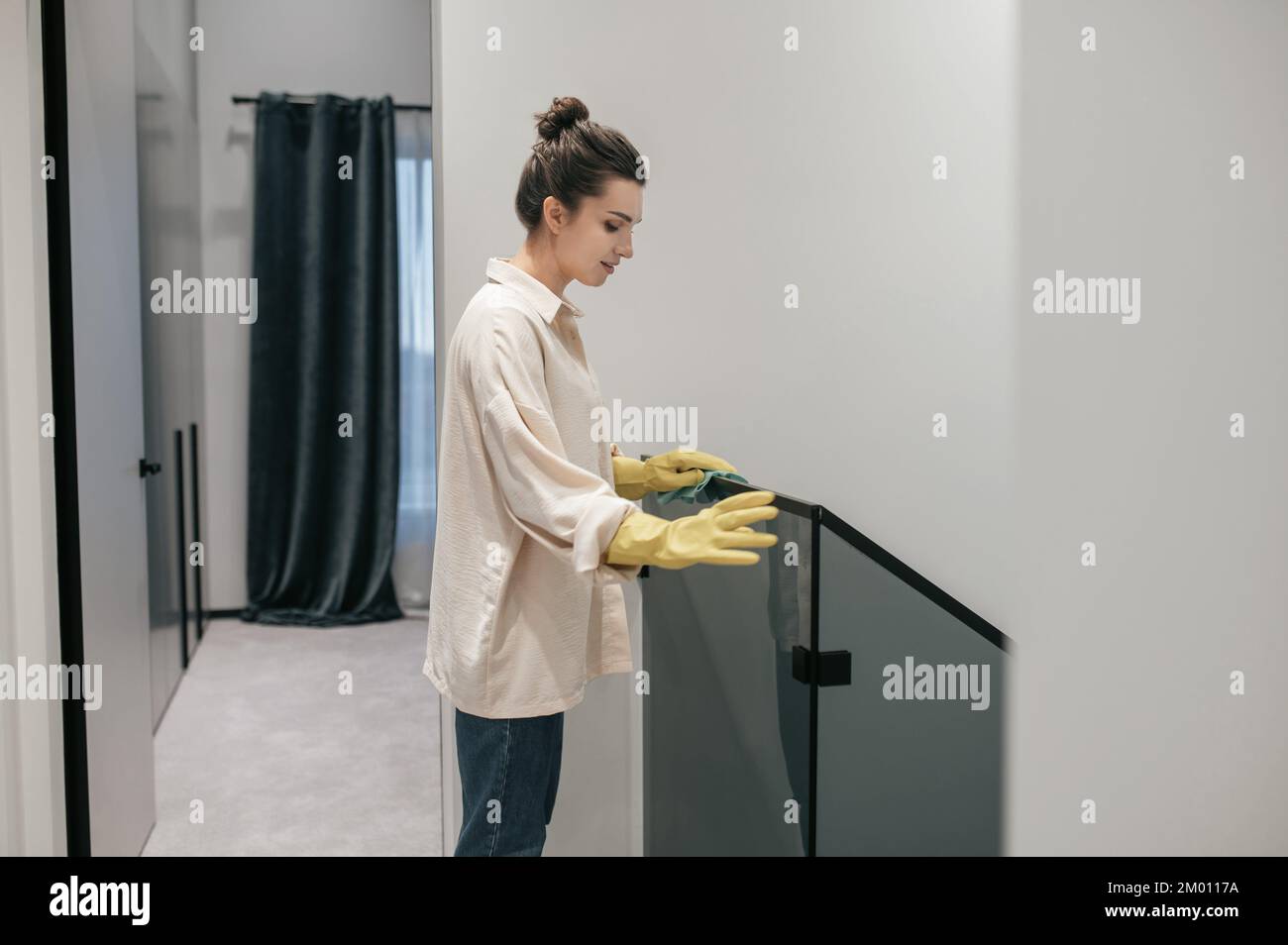 Housekeeping. Young dark-haired woman cleaning the stairs. Stock Photo