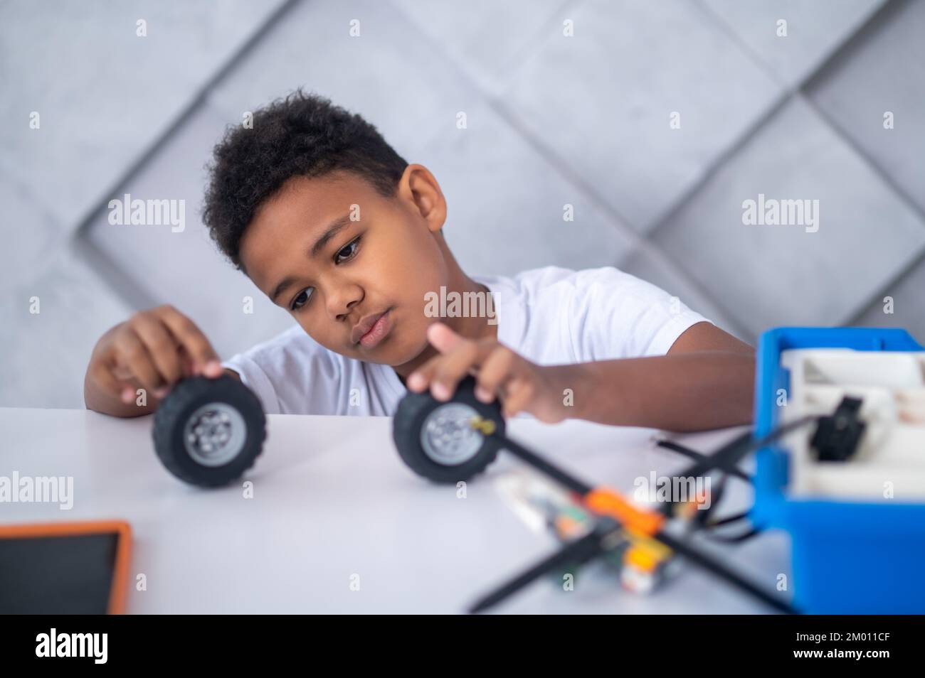 Toy wheels. A darkskinned boy playing with toy vehicle wheels Stock Photo Alamy