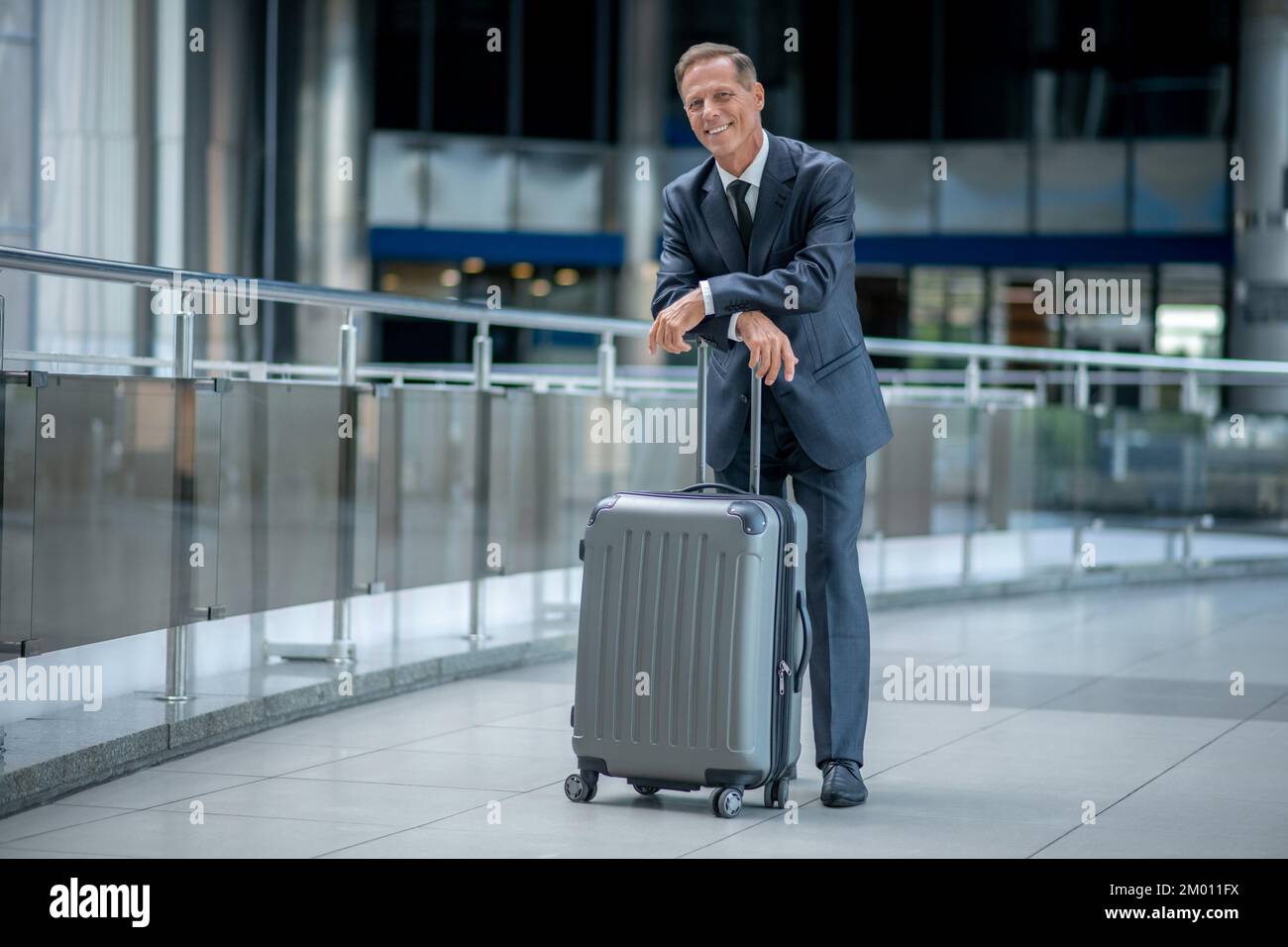 Travel. Middleaged man in business suit with suitcase standing