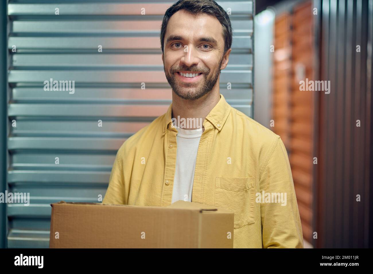 Portrait of a smiling joyous young worker posing for the camera in the storehouse. Stock Photo