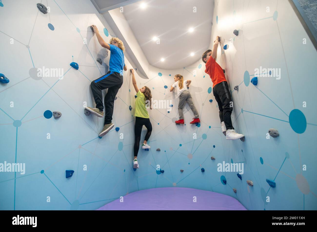 Wall climbing skill. Two girls and boys in sportswear deftly clinging