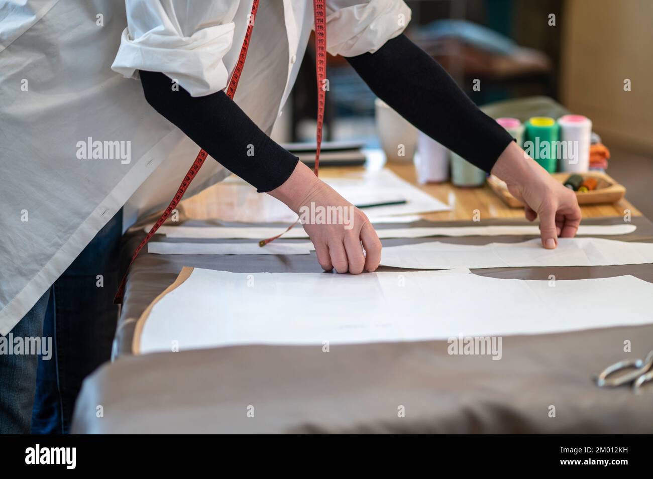 Tailor at work. Hands of tailor standing bending over table placing