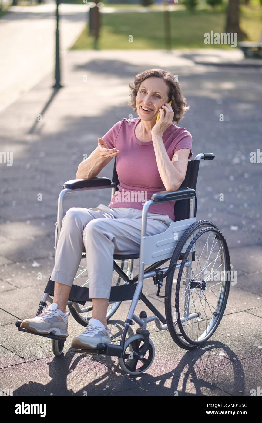 Phone call. Smiling woman on a wheel-chair talking on the phone. Stock Photo