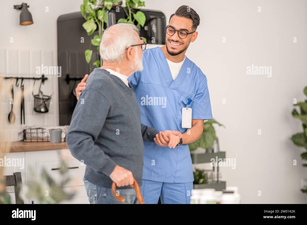 Caring medical worker dressed in uniform supporting a grayhaired