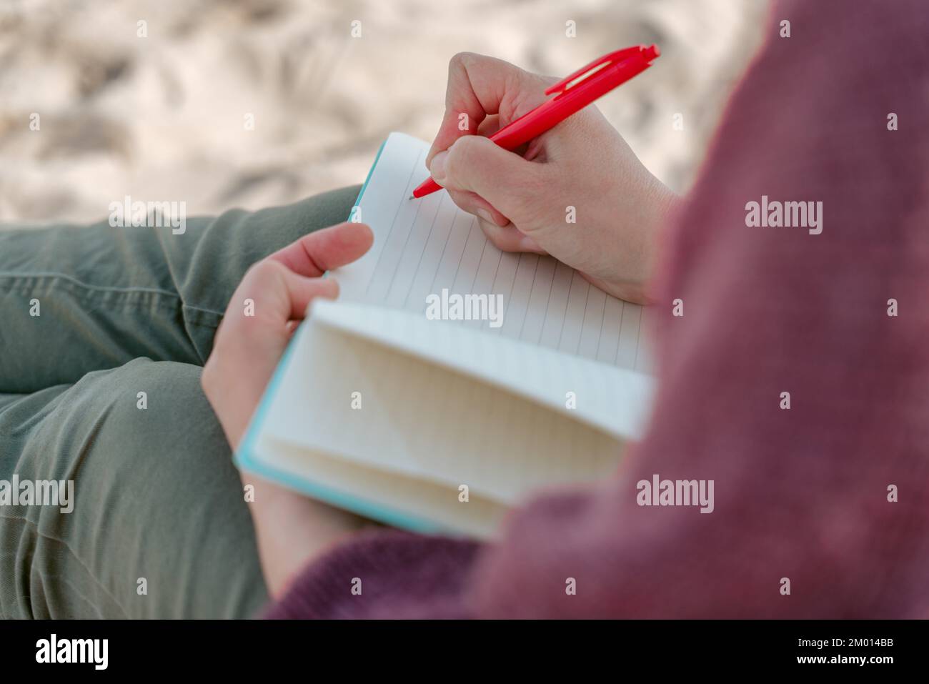 Cropped photo of a diarist writing with a pen on the blank page in the open notebook. Stock Photo