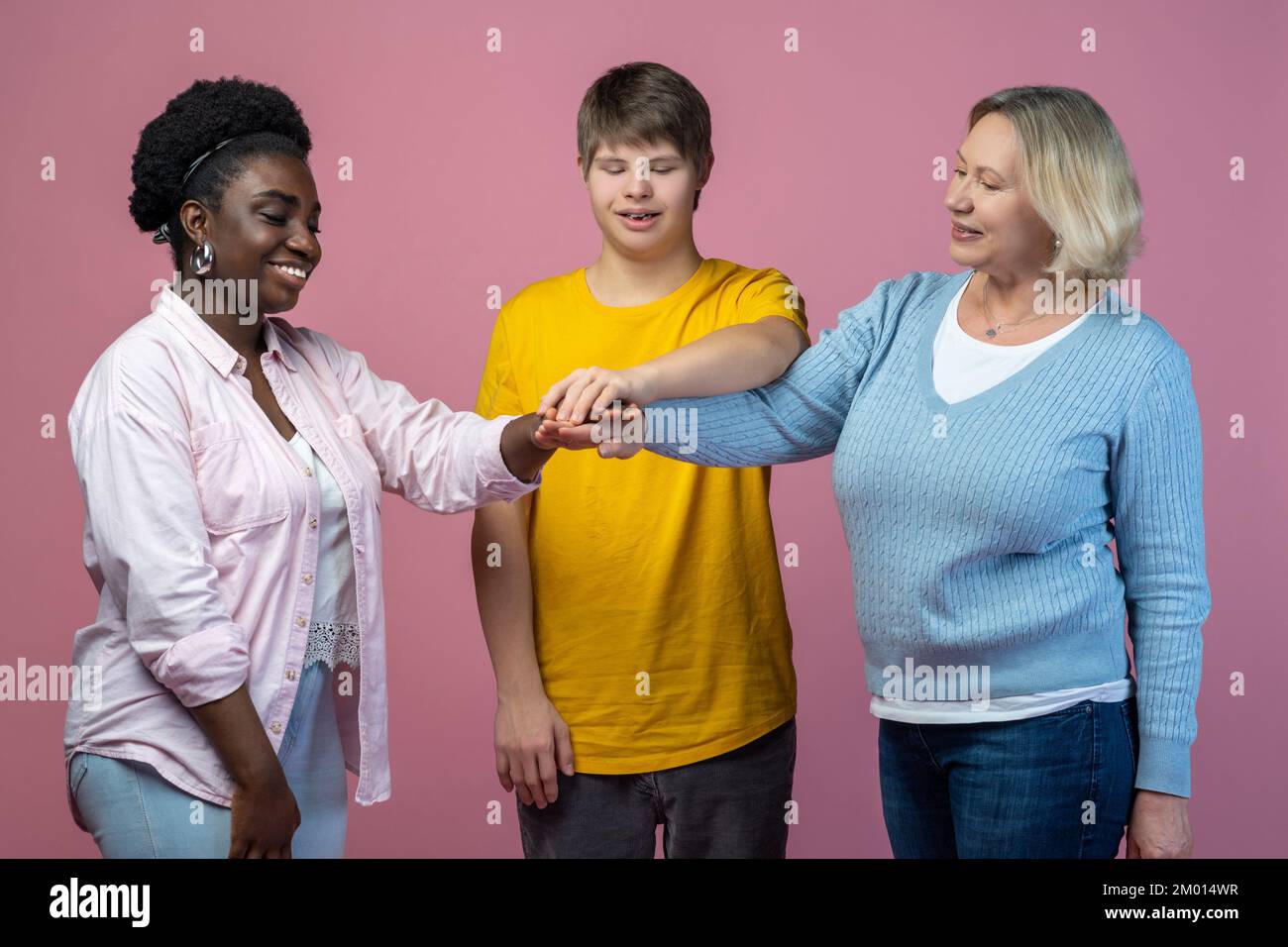Support. Smiling two women and guy with down syndrome standing with