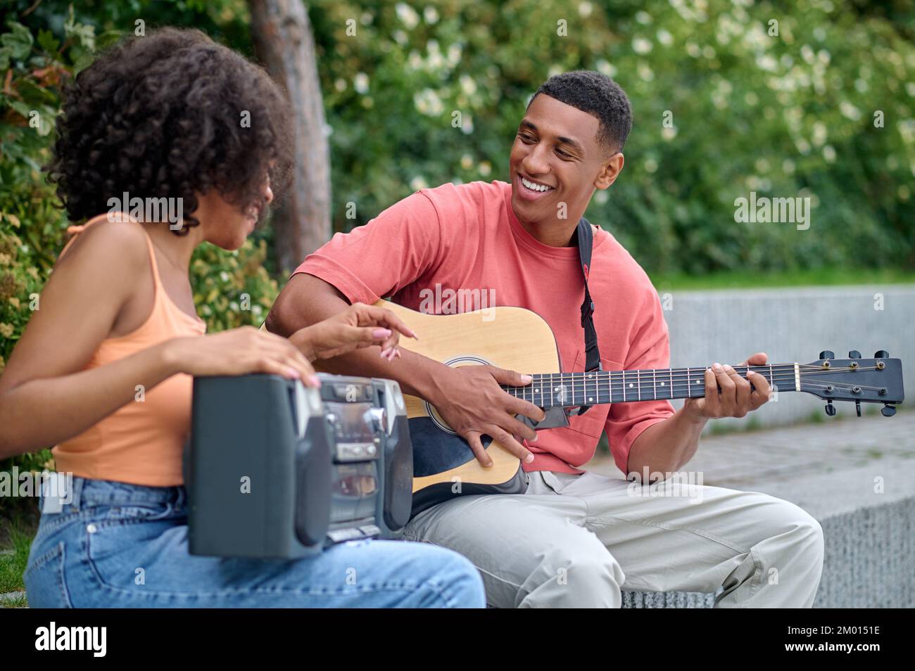 Passion for music. Darkskinned guy with guitar looking at girl with