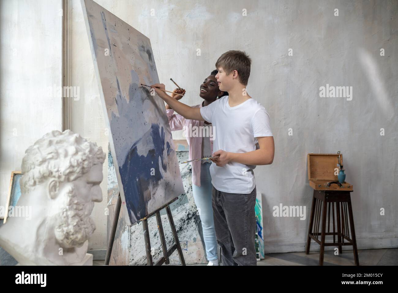 Painting. A tutor and a student near the easel looking positive. Stock Photo