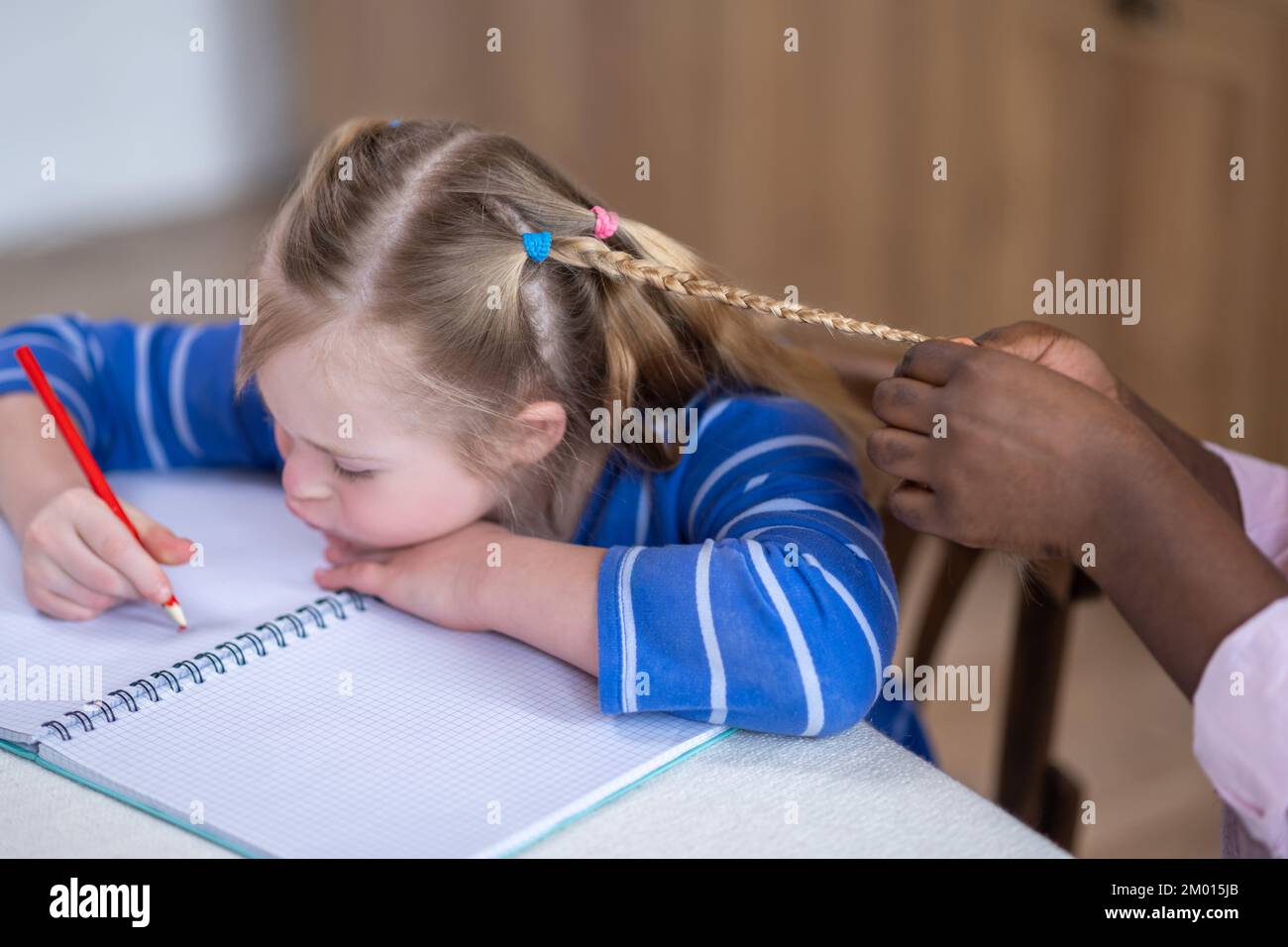 Hairstyle. Close up picture of females hands making pigtail to the girl. Stock Photo