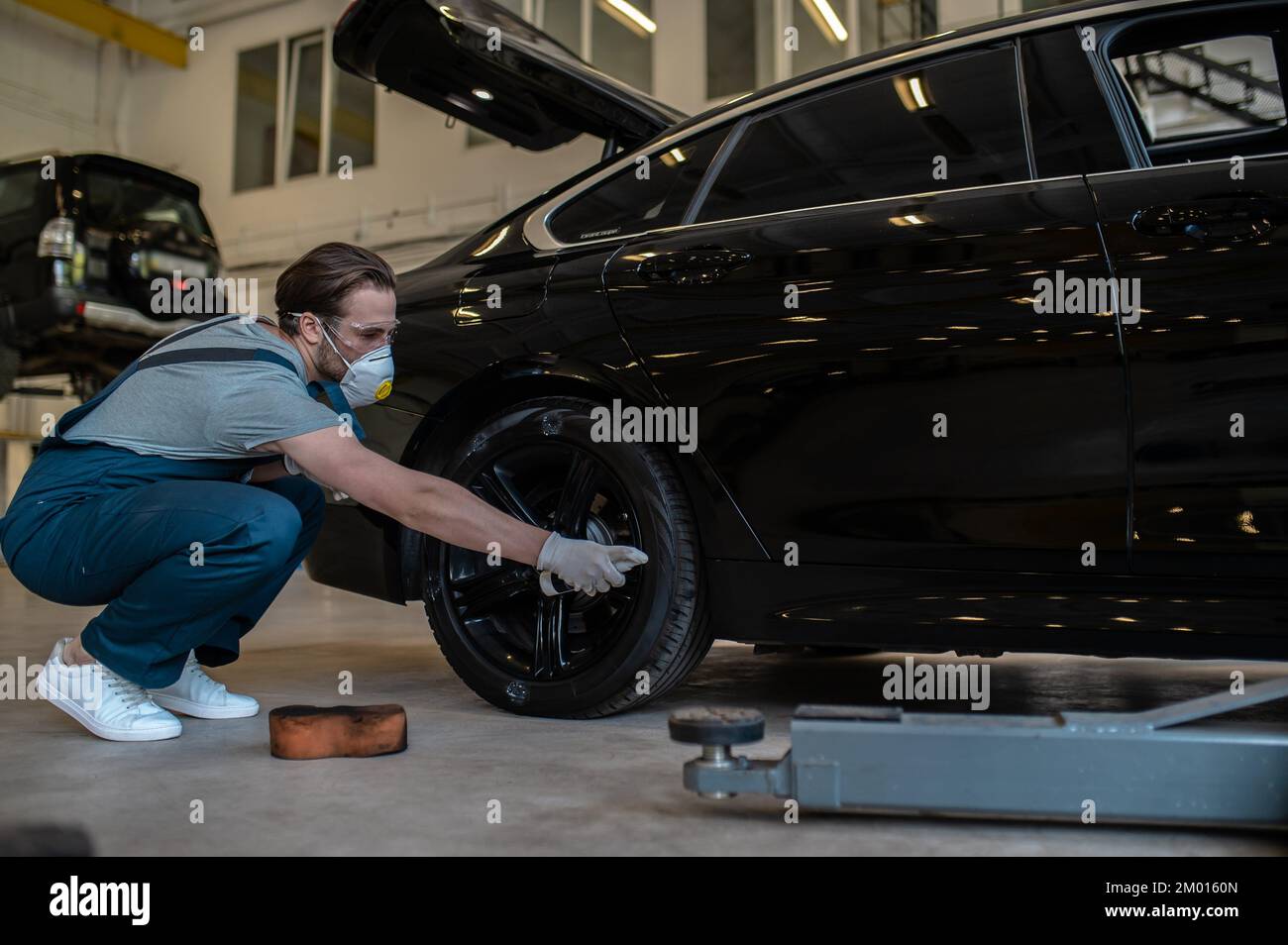 Experienced mechanic in the automotive respirator applying the tire