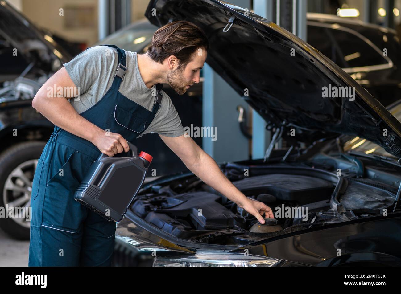 Engine oil change. Technician in the care service changing engine oil