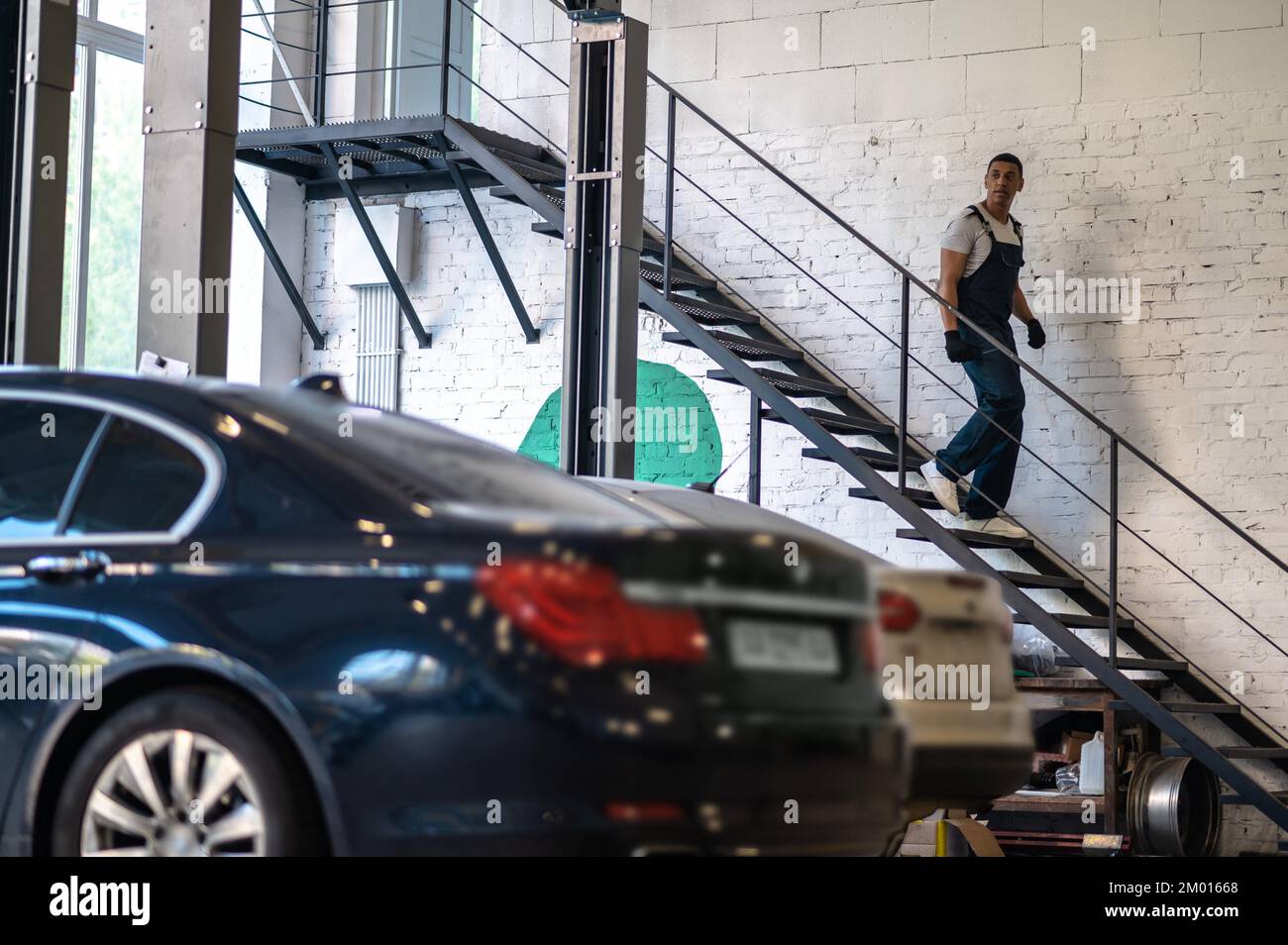 In the garage. Technician in woking clothes going downstairs in the