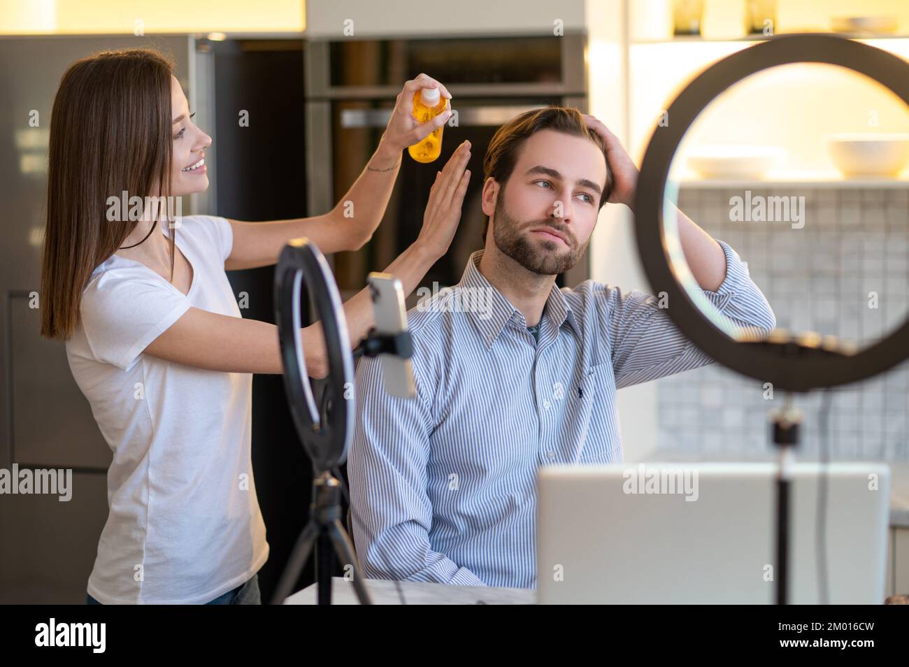 Appearance. Long-haired woman making hair to a man before webinar. Stock Photo