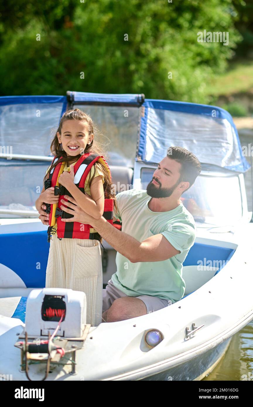 Before the boat trip. Man putting on a life vest on his little daughter