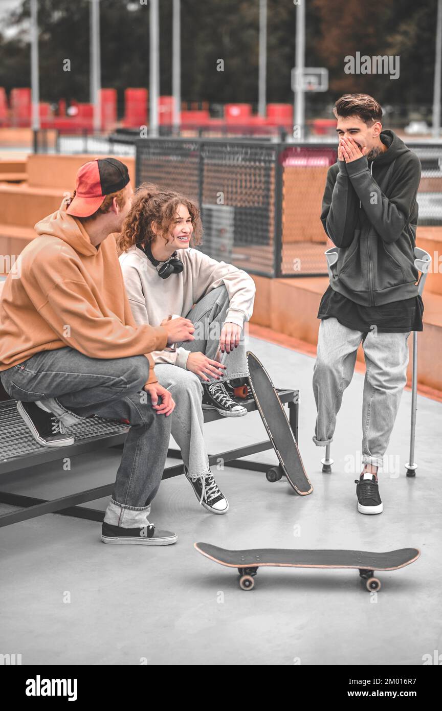 Cheerful conversation. Girl redhaired guy and friend with disability