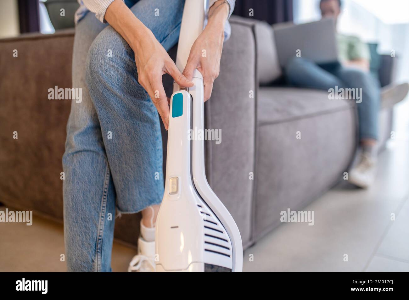 Ease of use. Female graceful hands touching modern vacuum cleaner near