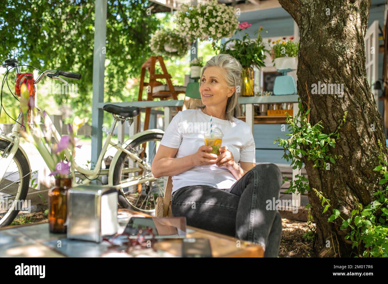 Cocktail in the yard. A mature woman sitting outside and drinking her cocktail Stock Photo Alamy