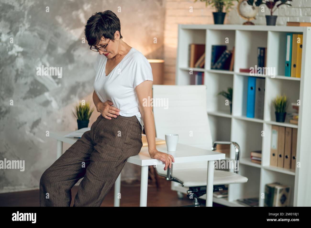 Menopause. Mature shorthaired woman suffering from pains in stomach