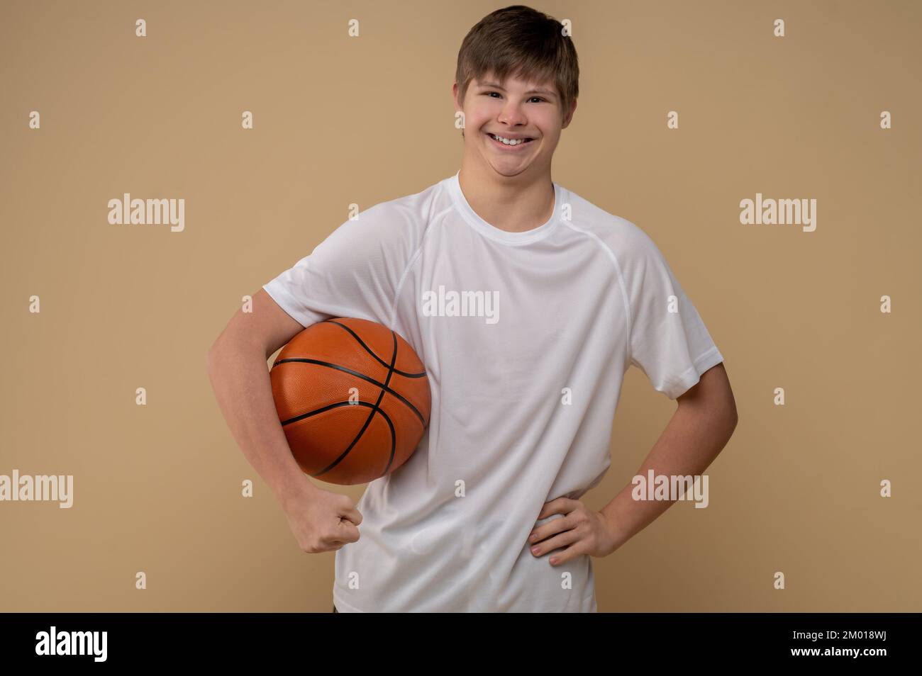 Smiling happy teenage boy with the round rubber game ball under his