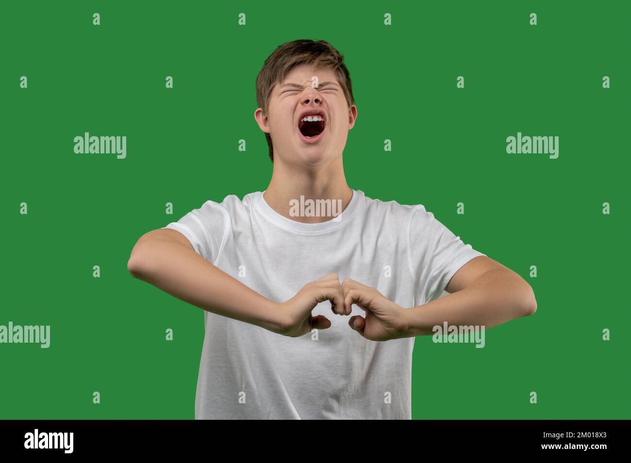 Waist-up portrait of an emotional teenager shouting with his eyes closed and making a hand gesture. Stock Photo