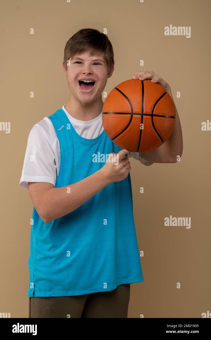 Front view of a joyful adolescent spinning the game ball on the tip of