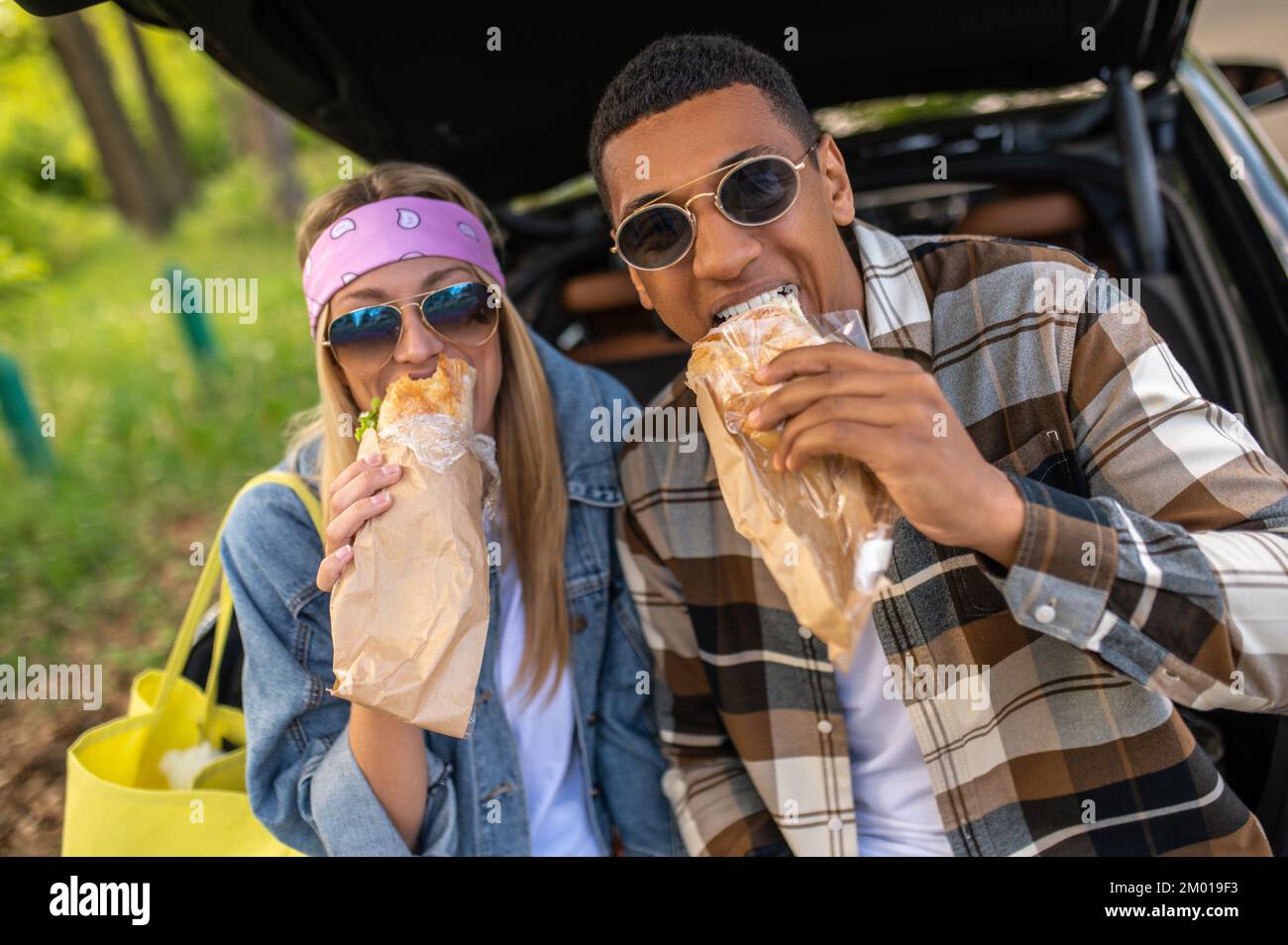 Lunch time. Young man and woman eating sandwiches and looking contented