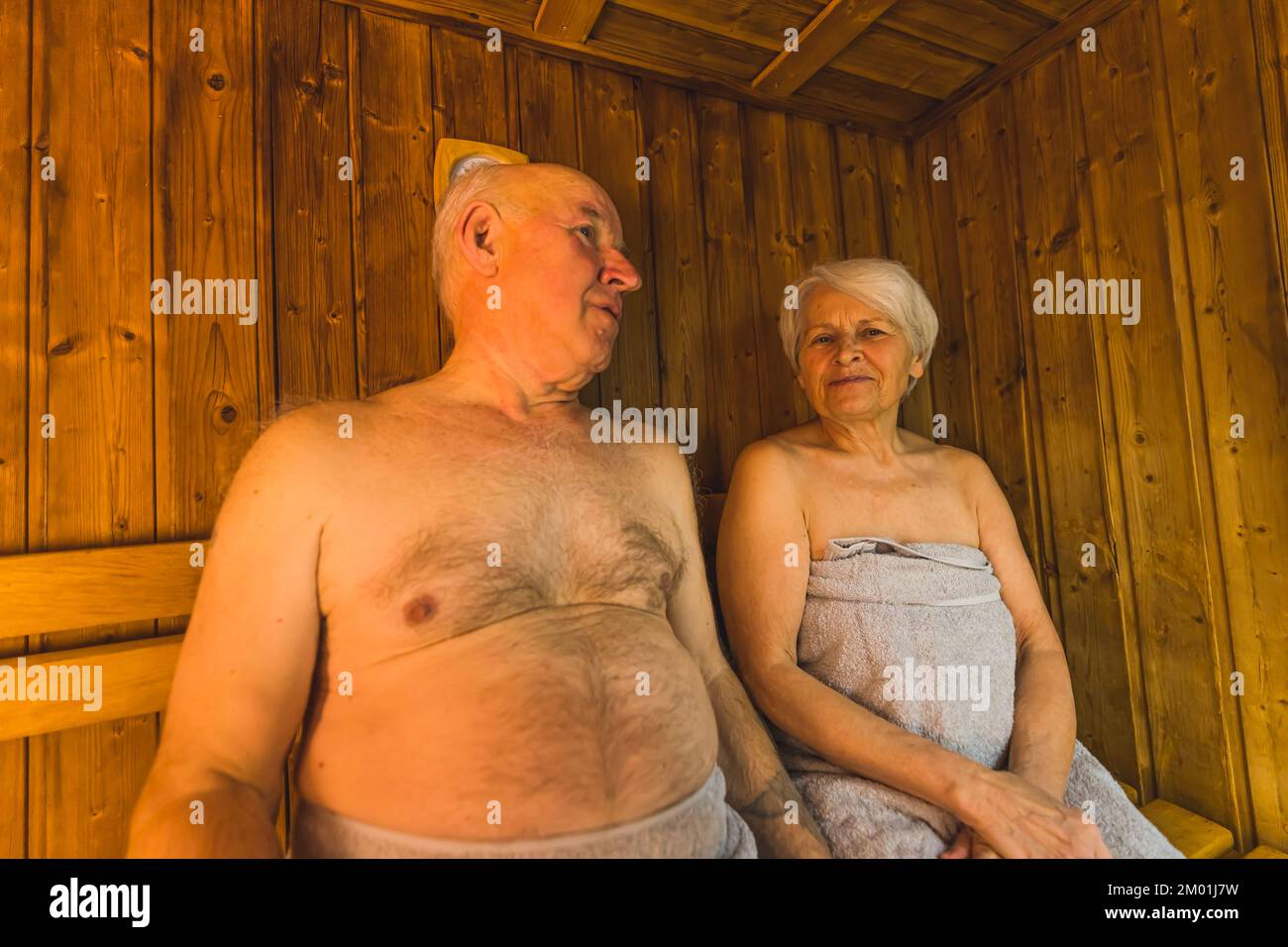 Idea for a gift for grandparents. Sauna and SPA day. Indoor medium closeup shot of two caucasian senior adults sitting together in a sauna,. High quality photo Stock Photo